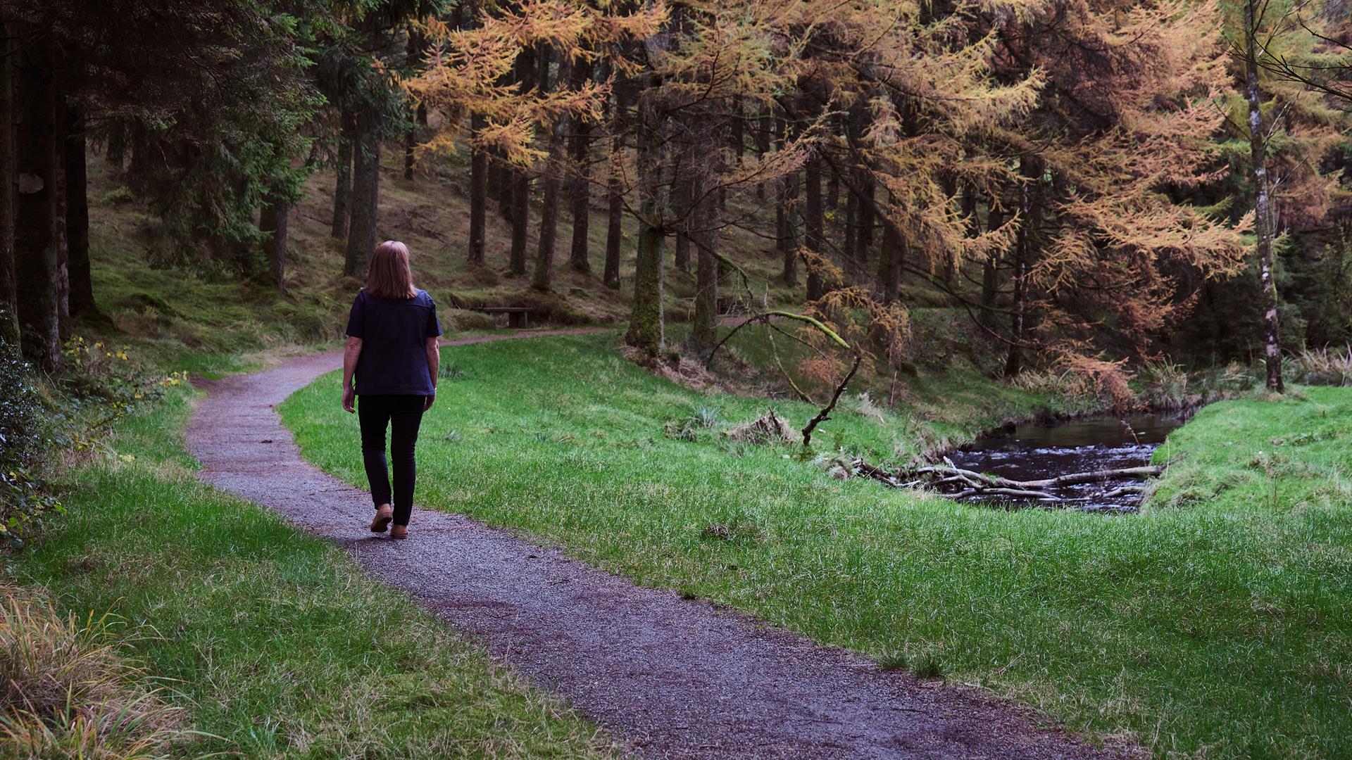 A woman walking along a path in Davagh Forest.