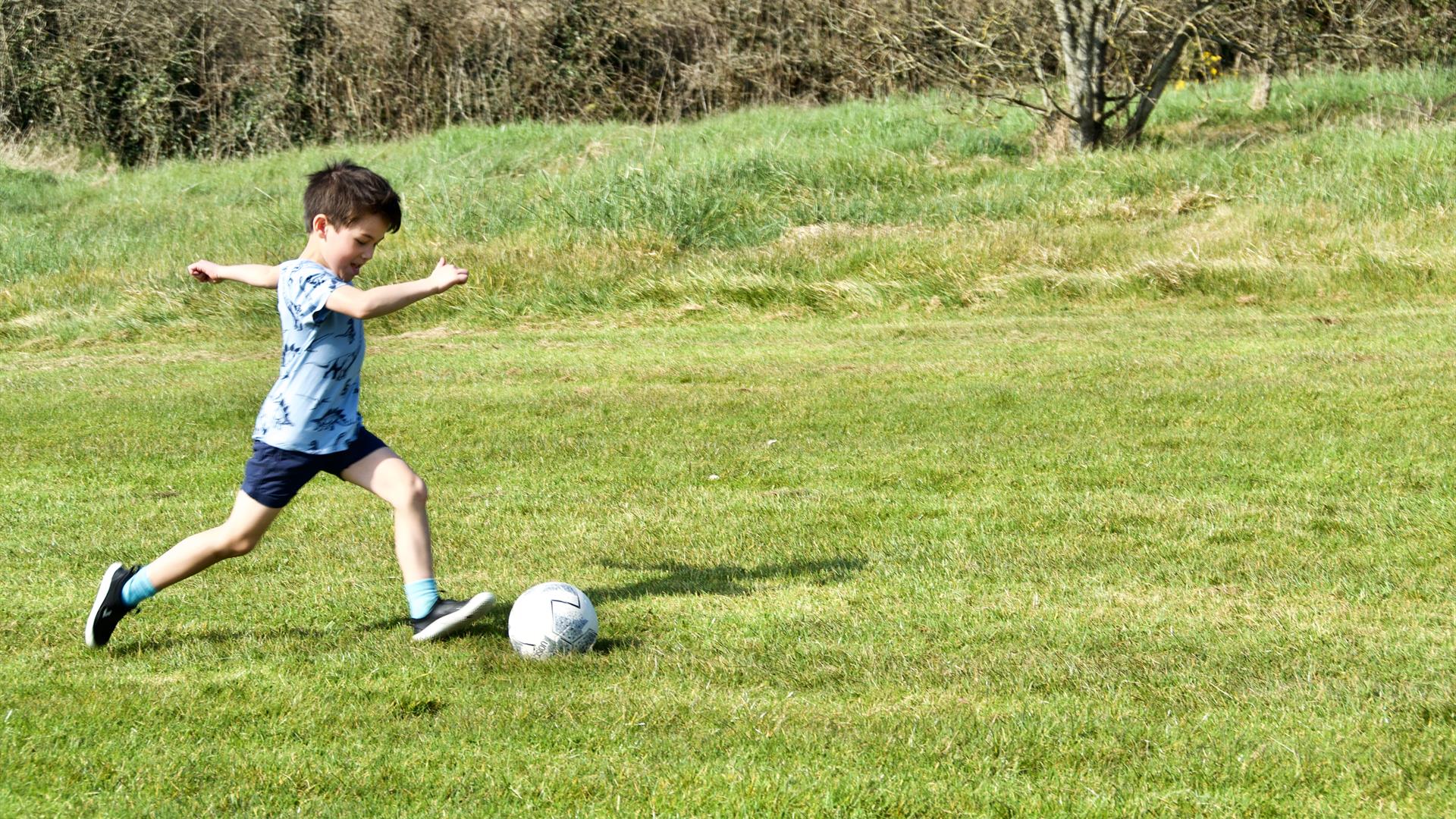 young boys kicks football at Newtownabbey footgolf