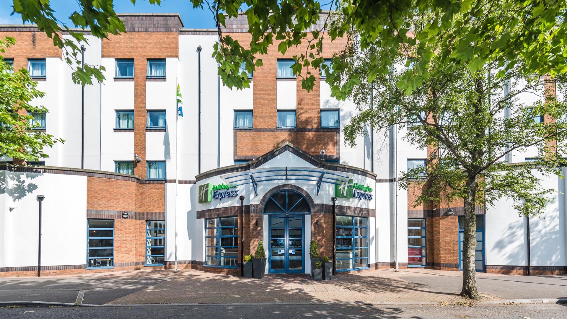 Photo of the exterior of the Holiday Inn Express Belfast City, Holiday Inn Express sign on the façade and trees on the sidewalk.