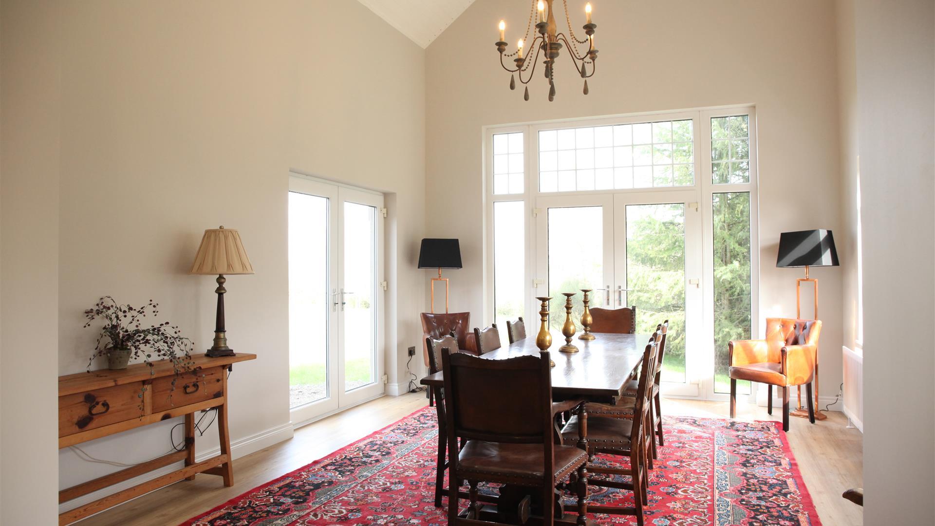 Image shows large dining room with table and 8 chairs. Patio doors onto garden area