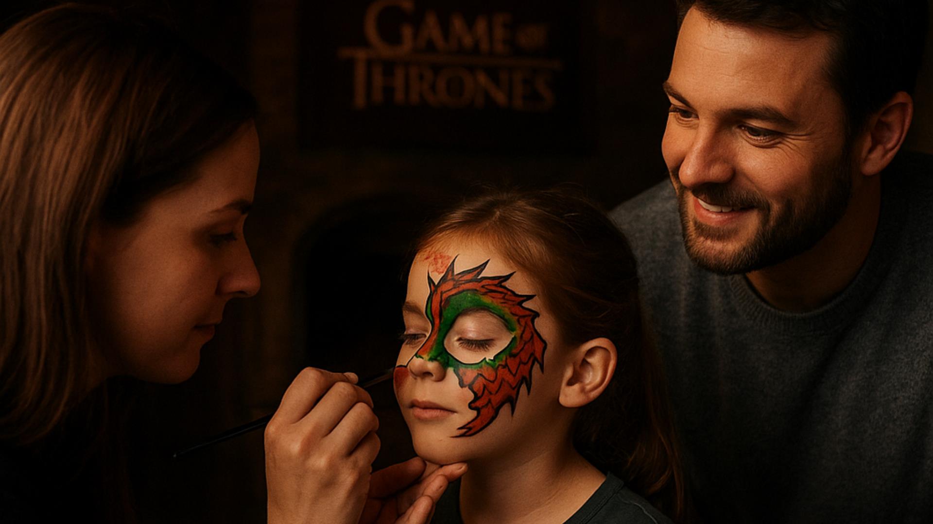 Woman painting a dragon on child's face as father watches.