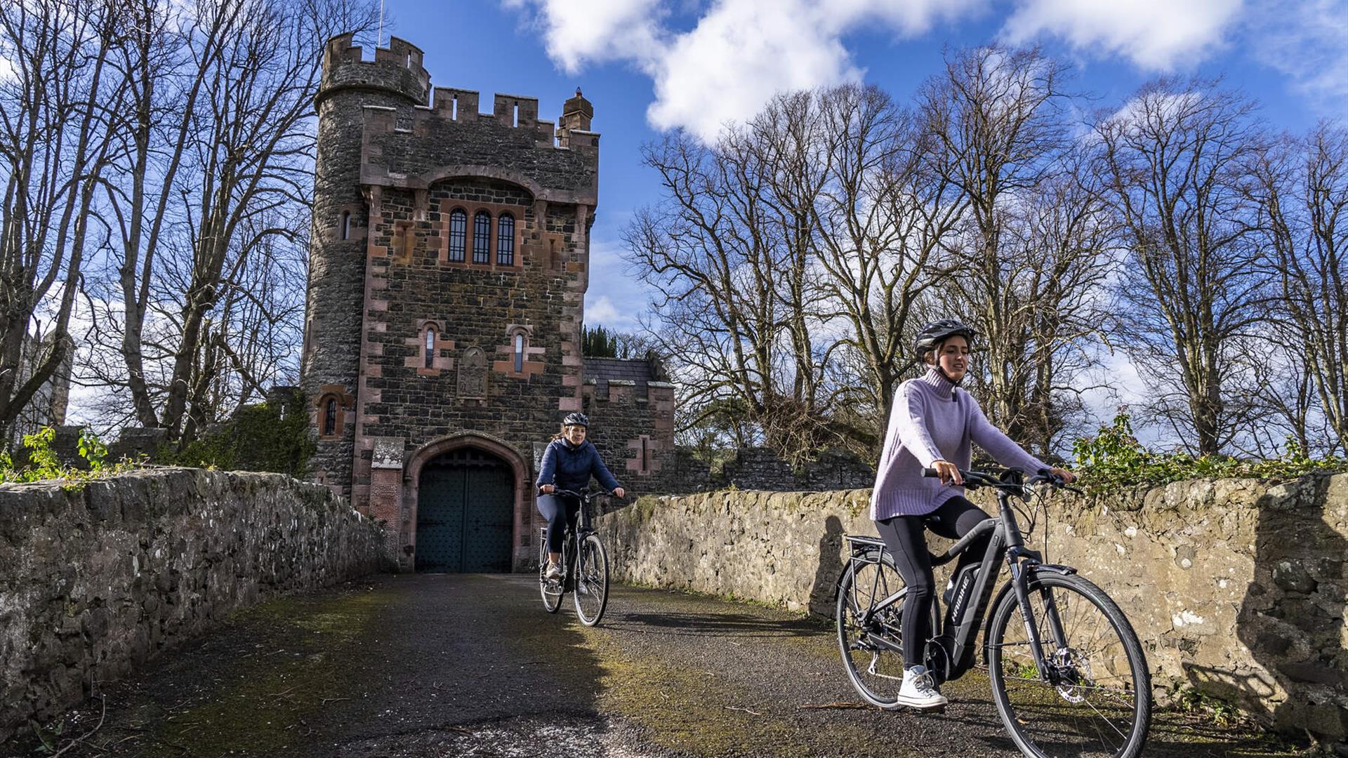 Two cyclists on the bridge that leads to the Barbican Gatelodge