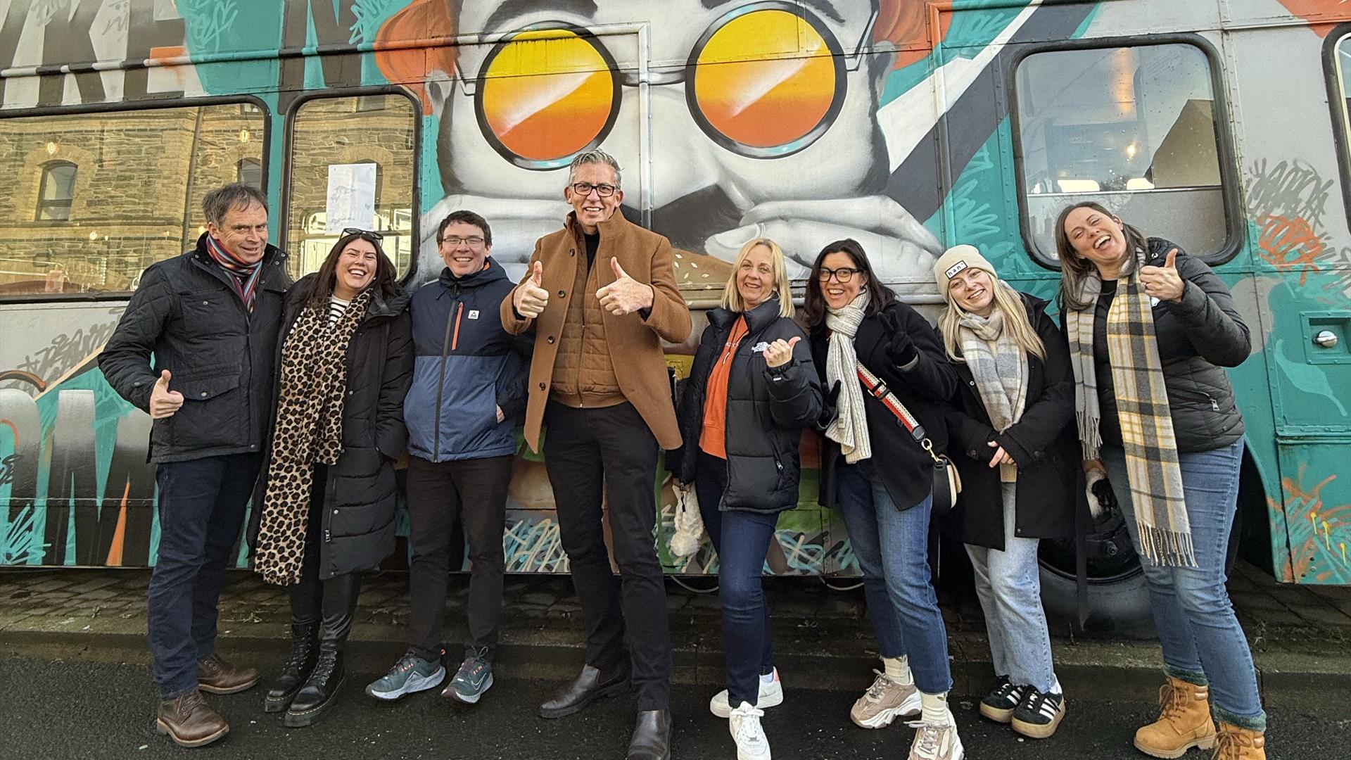Group shot outside of pyke n pommes double decker bus restaurant