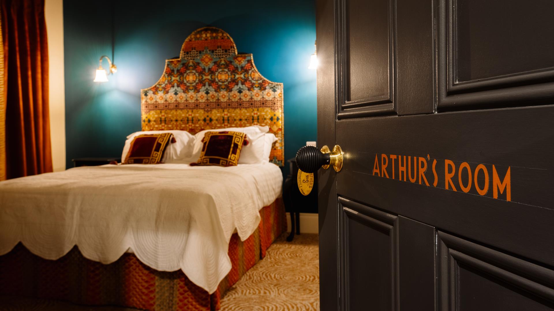 Picture of Arthur's suite inside Arthur's Guesthouse with carefully made double bed and side lamps on the walls