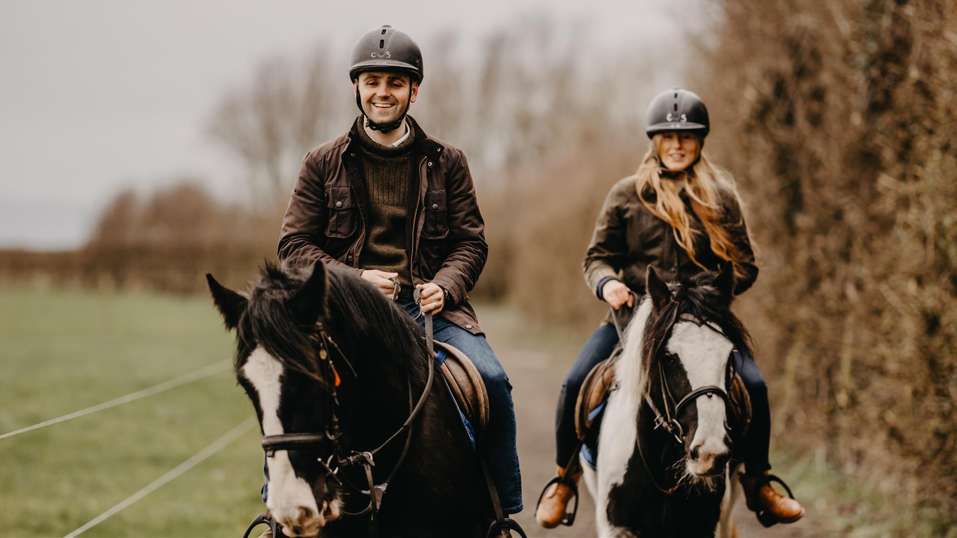 a man and woman on horseback on a countryside trail