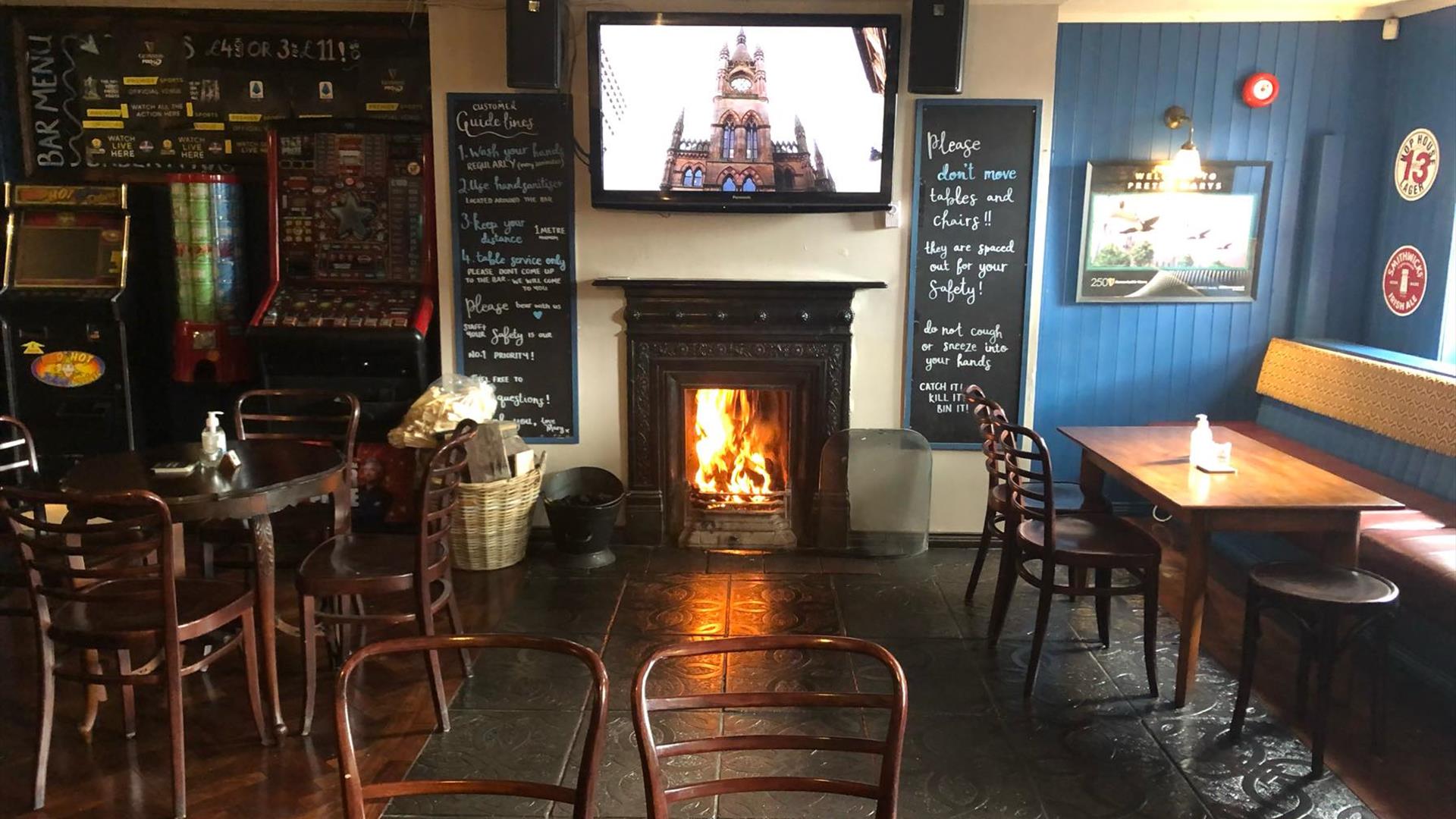 Image is of the lounge area of the bar with open fire blazing and table and chairs