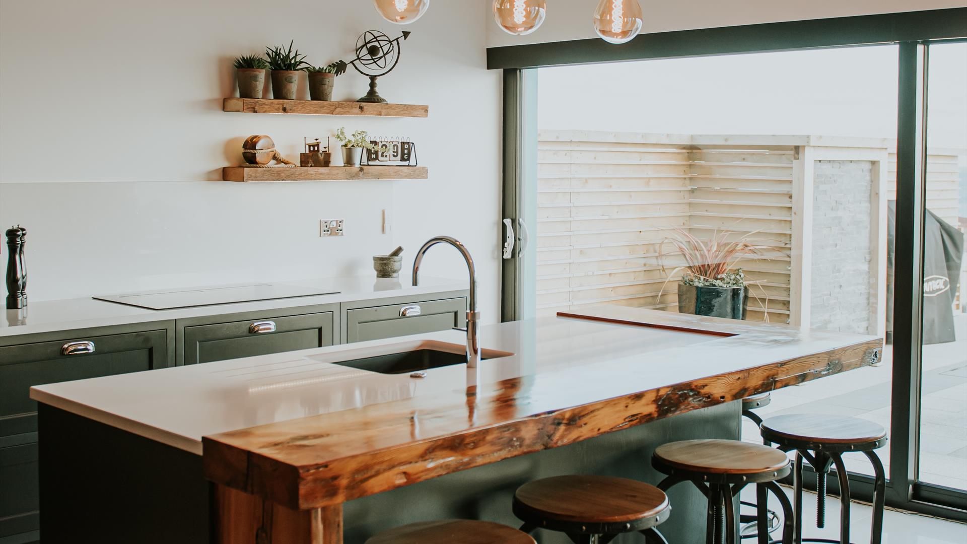 Luxury, bespoke kitchen area with a breakfast bar and large sliding doors onto a patio area.