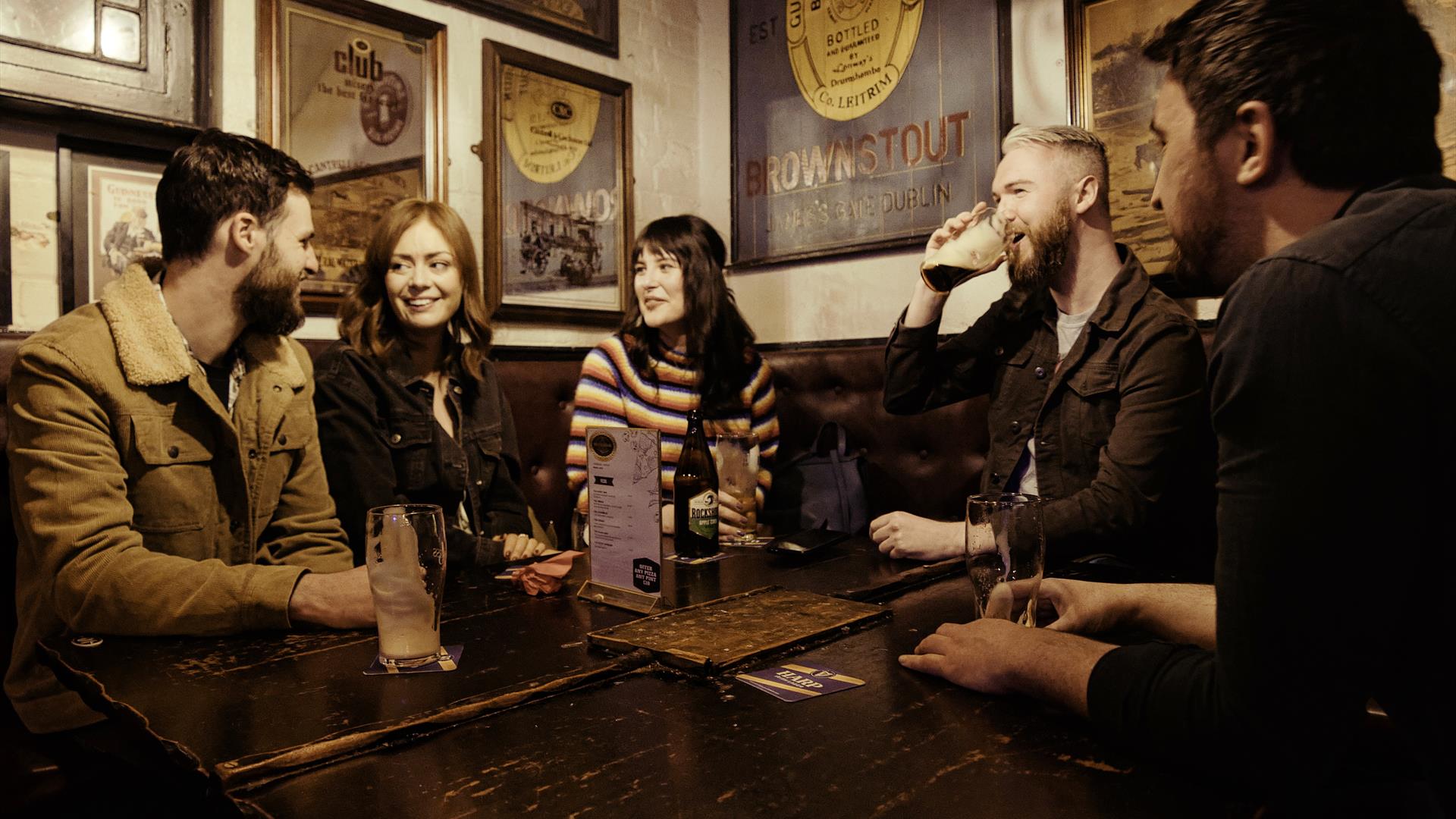 group of people at a table inside the bar chatting and enjoying drinks.
