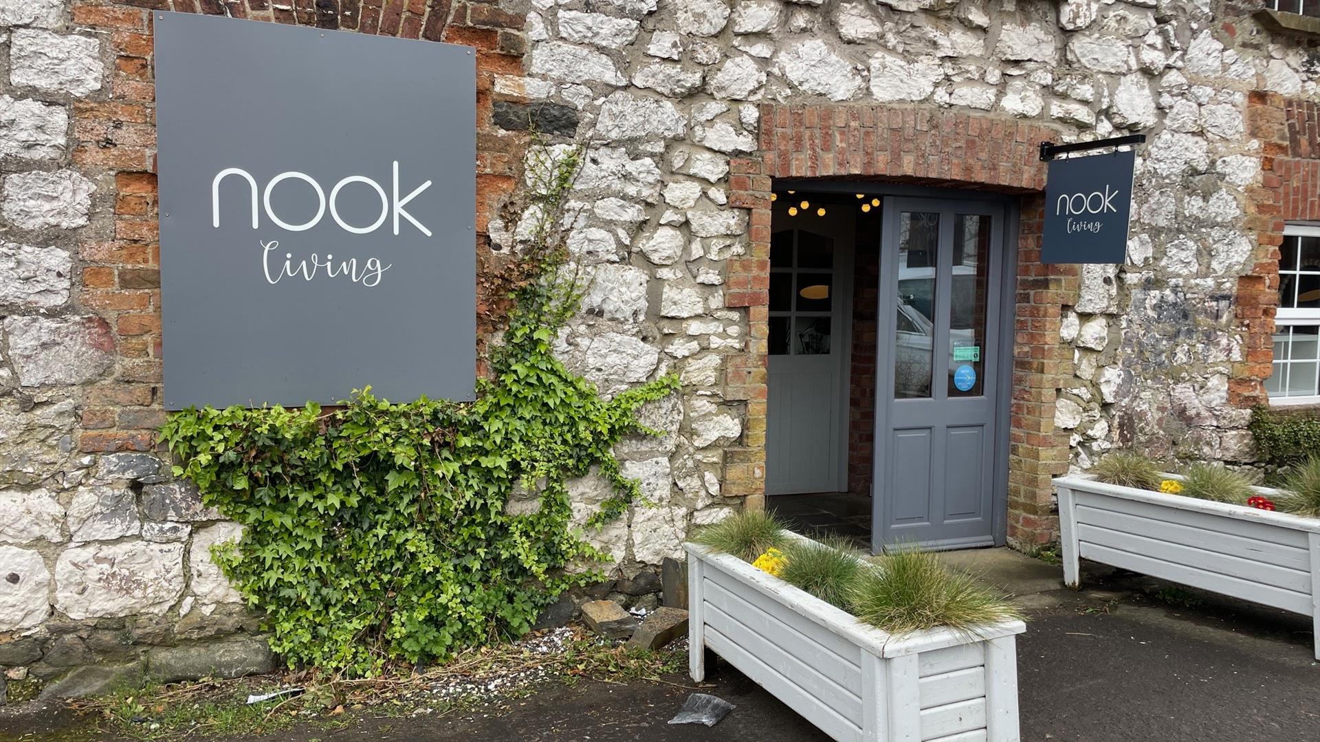 Brick exterior of Nook Living with grey signage and white planter