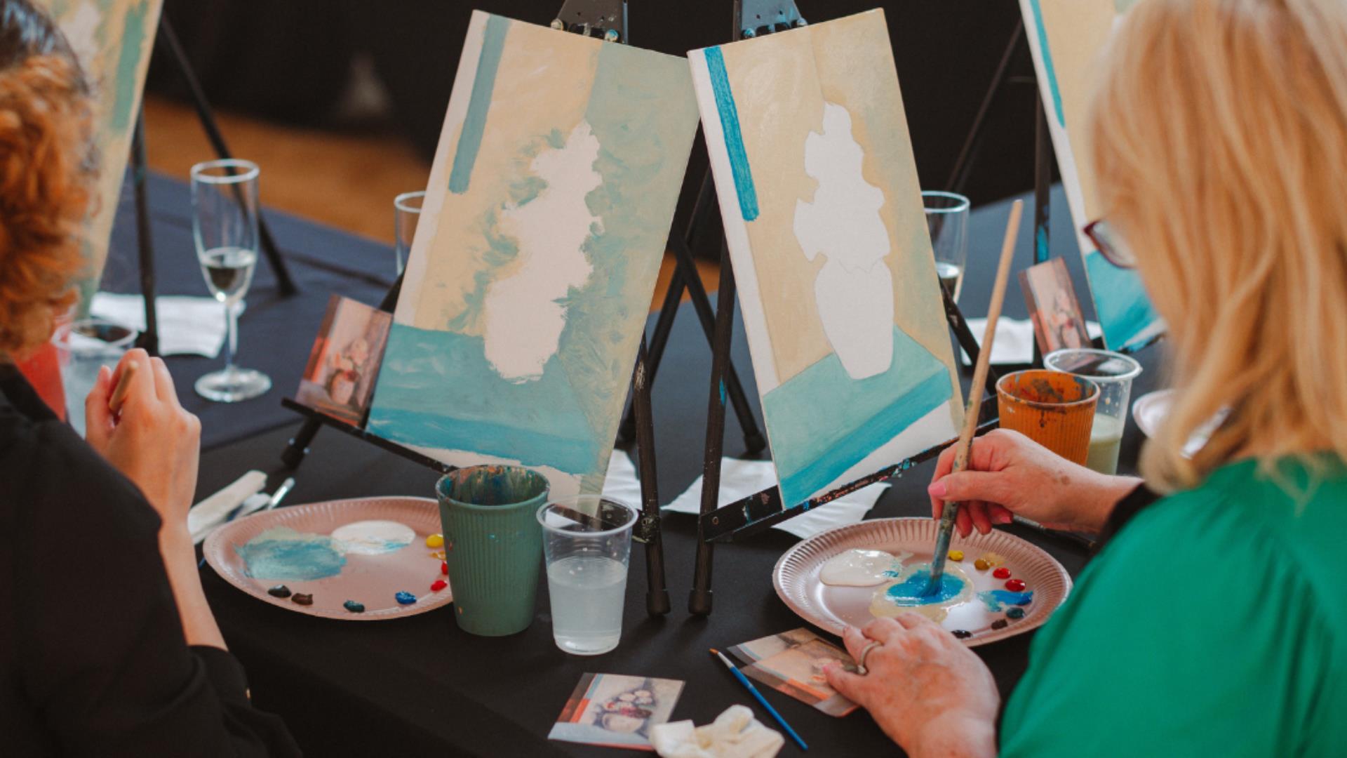 Image of a paint & prosecco session at the Ulster Museum showing two women painting canvases.