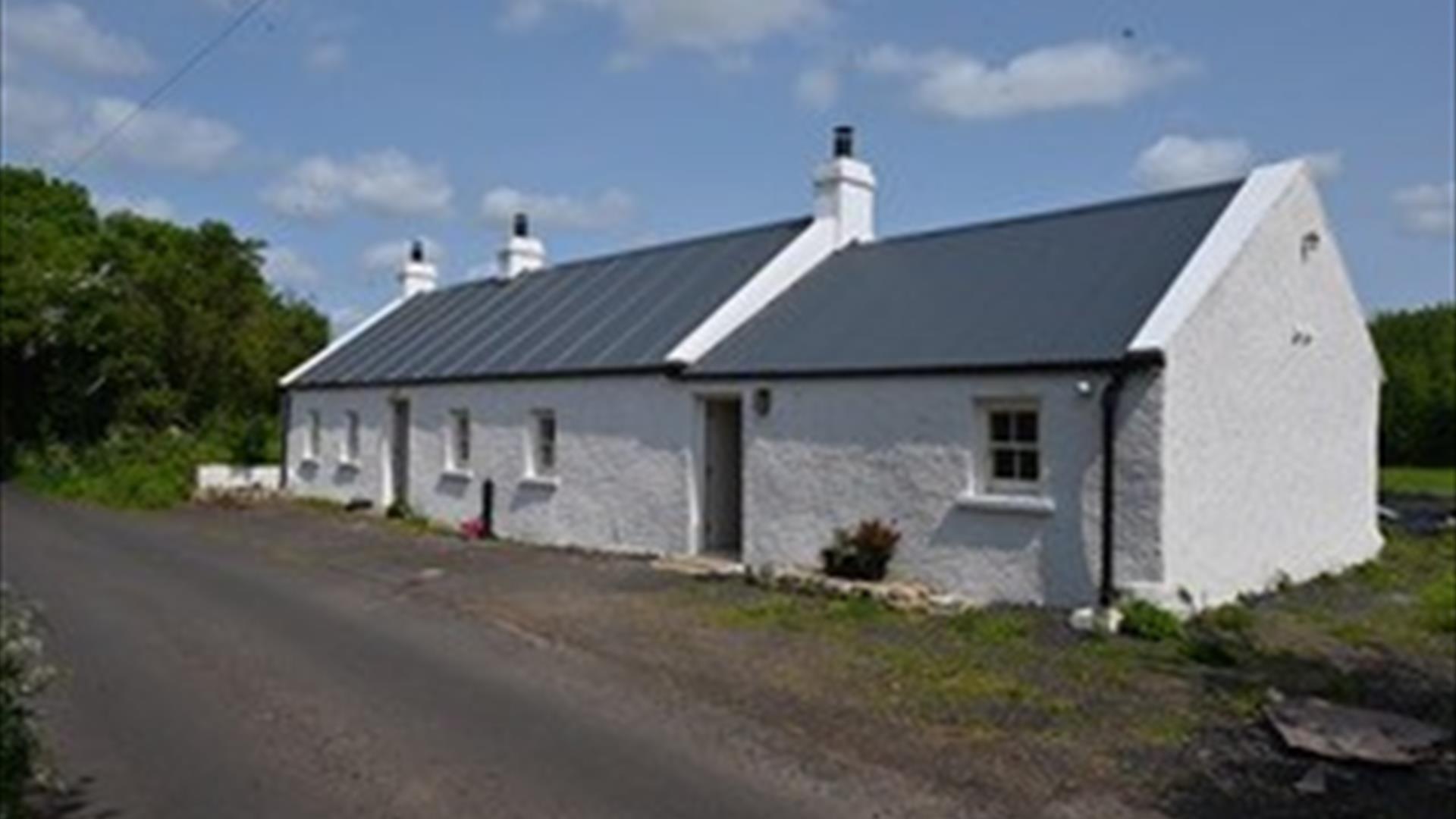 A traditional white country cottage at the roadside.