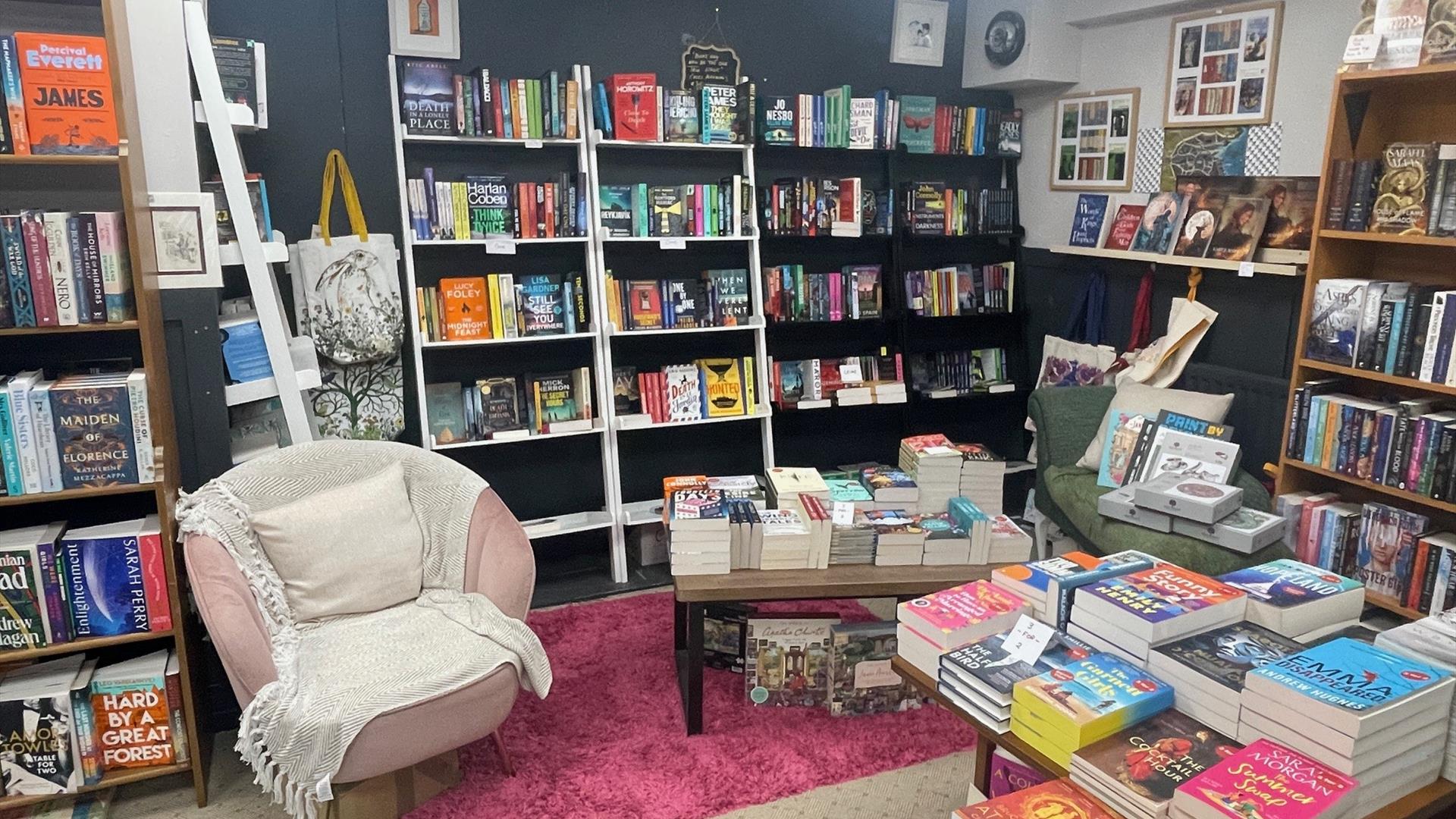 Pink seat with white rug and cushion surrounded by shelves and tables with books