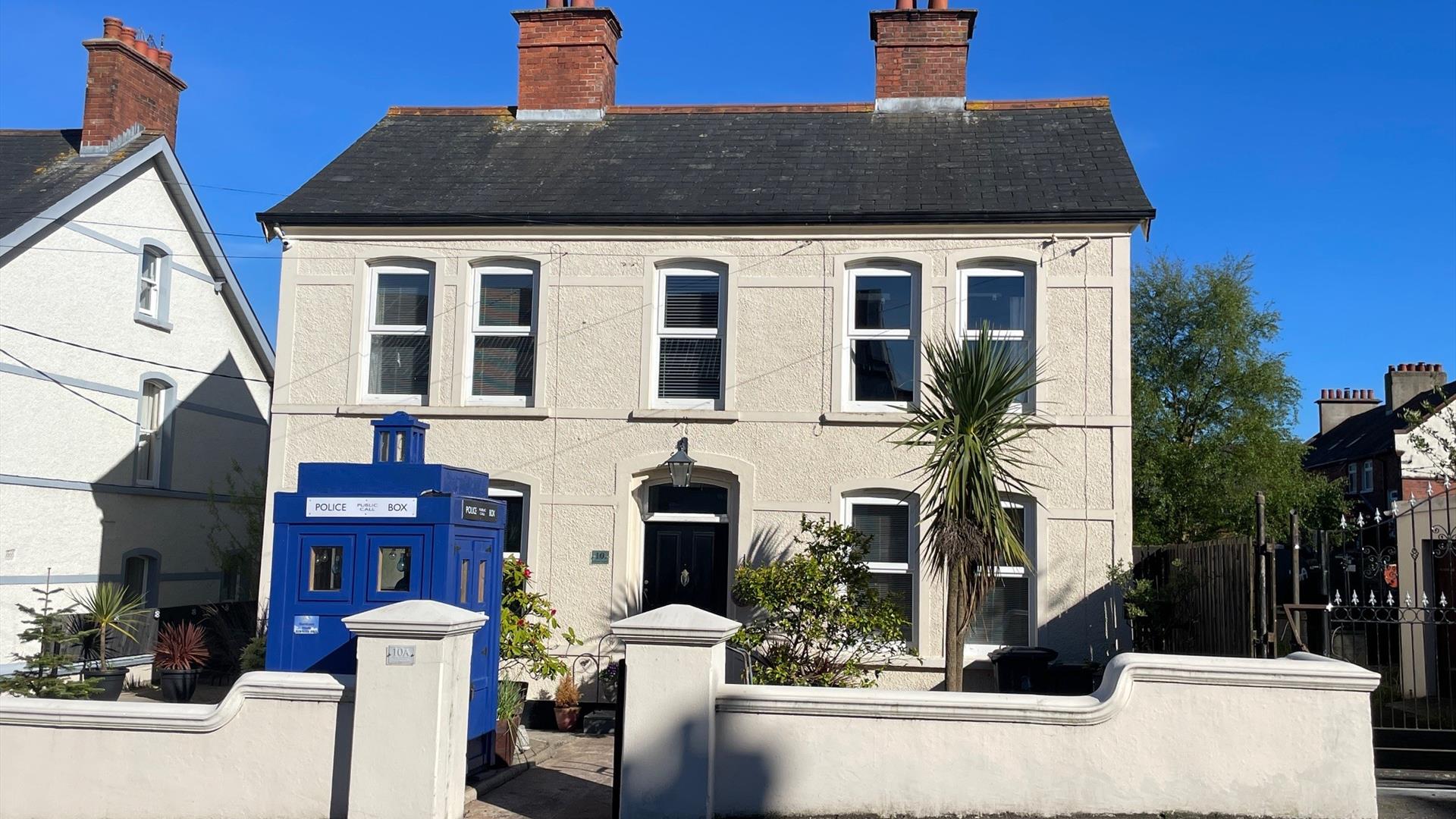 White exterior of Sergeants House with old style blue police box as feature in garden