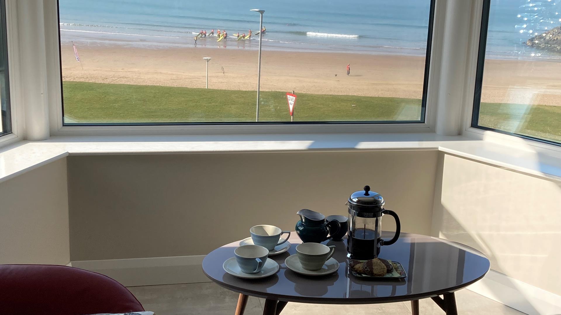 Seating area in front of window overlooking the beach and sea.