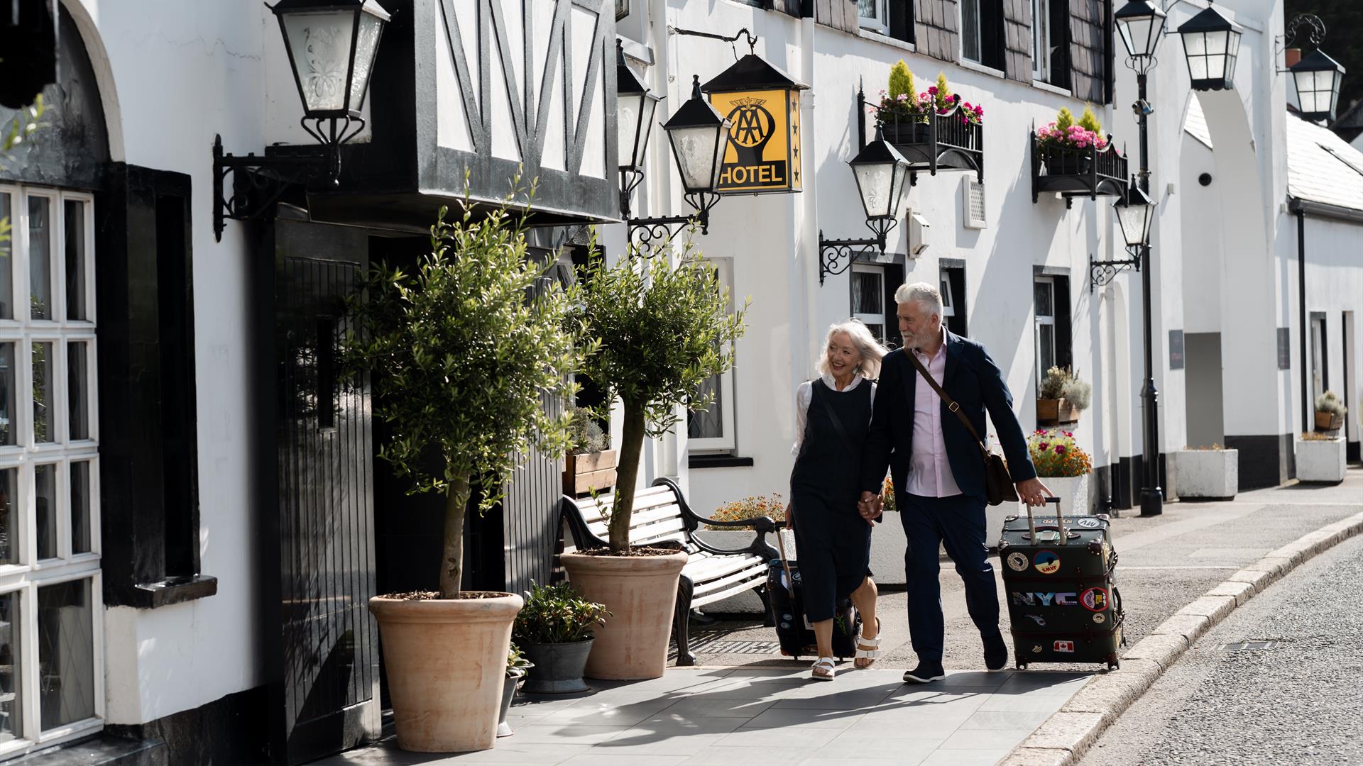 A couple pulling overnight bags entering into The Old Inn