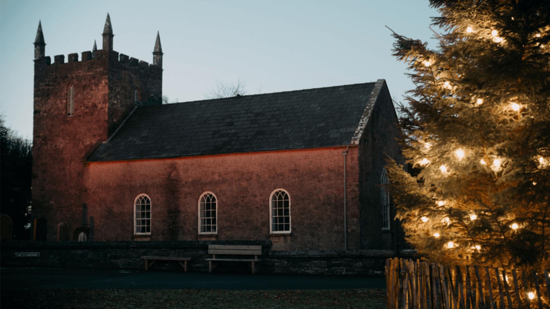 A picture of Kilmore Church at Ulster Folk Museum with a christmas tree at night