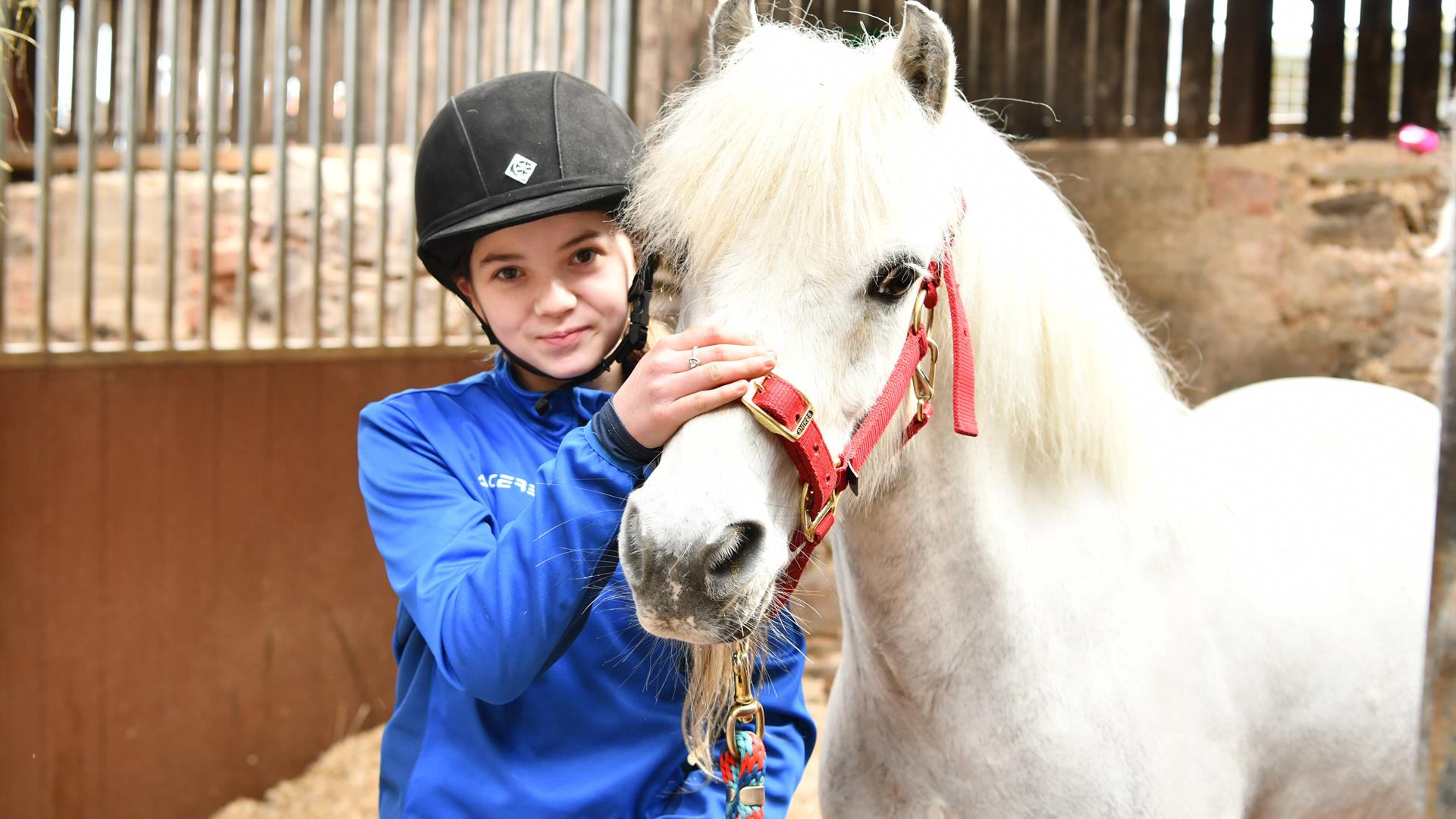 a girl standing with a white hose in the stables