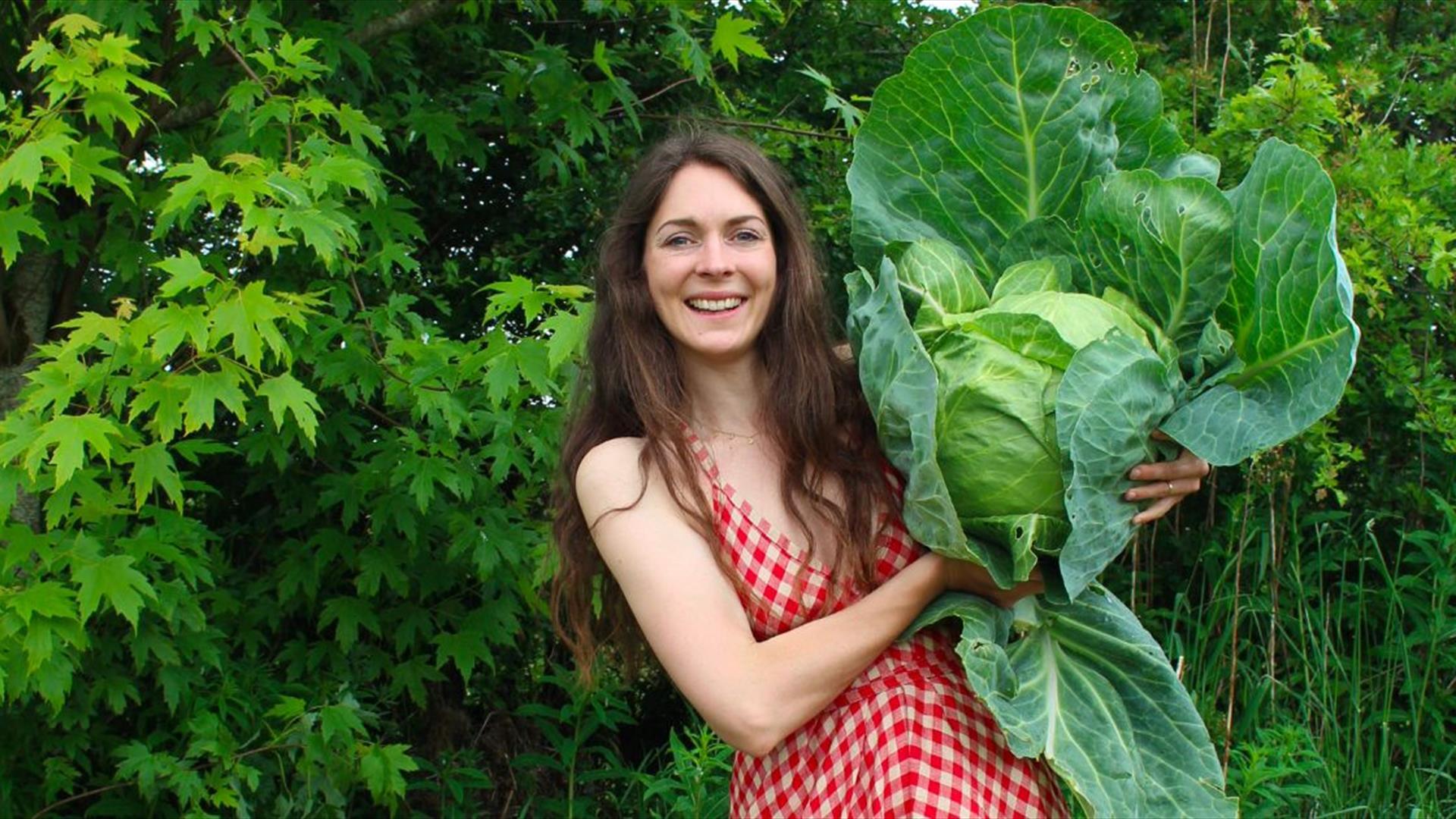 a woman holds a large cabbage