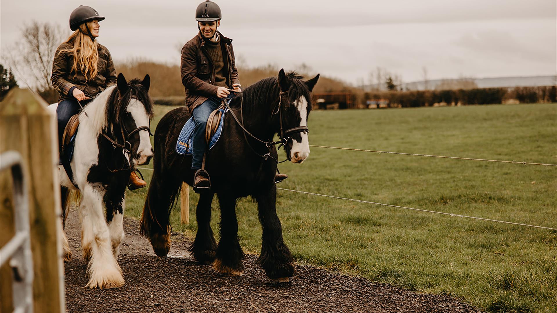 a man and woman on horseback in the countryside