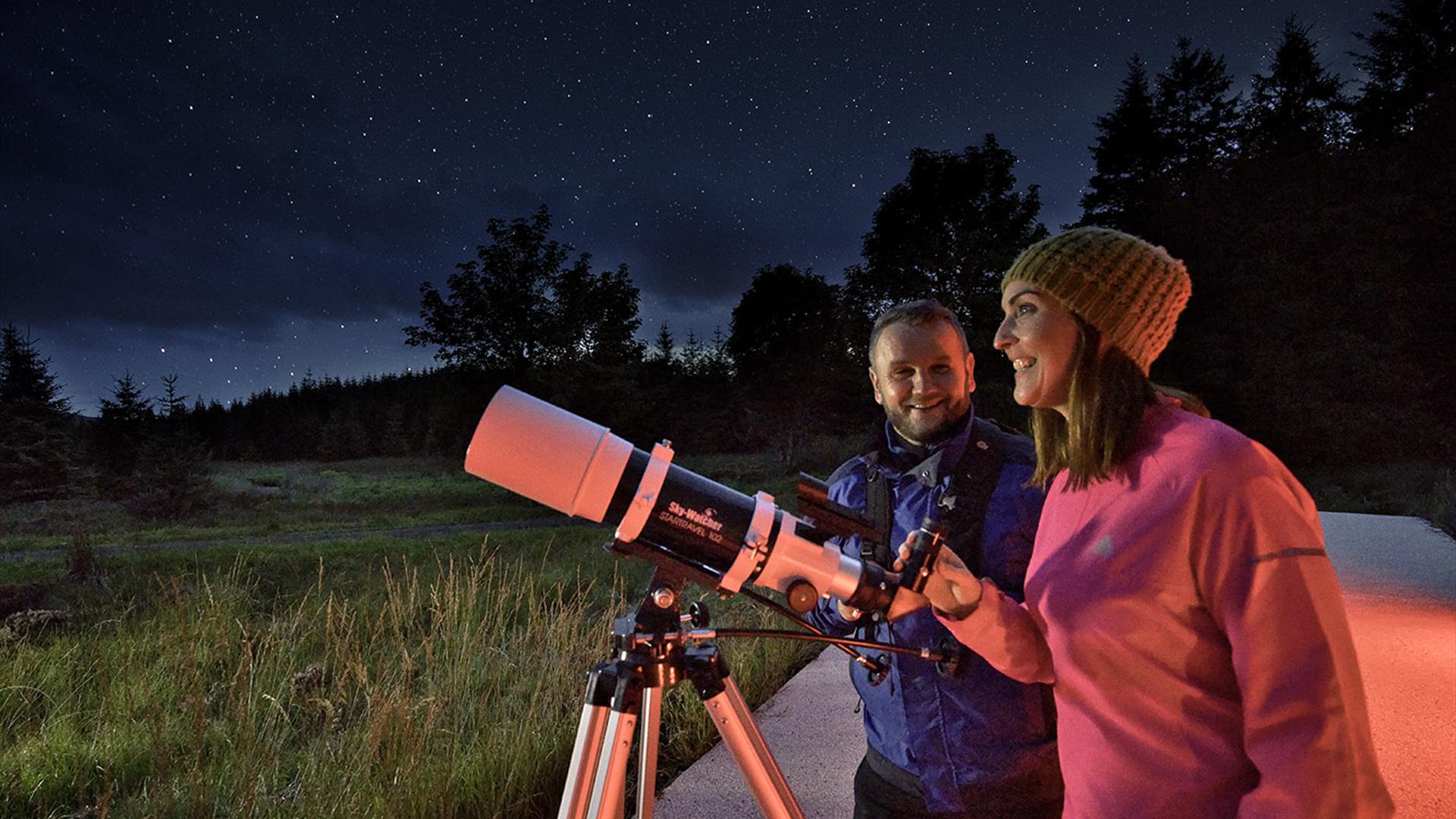 A smiling couple with a telescope 