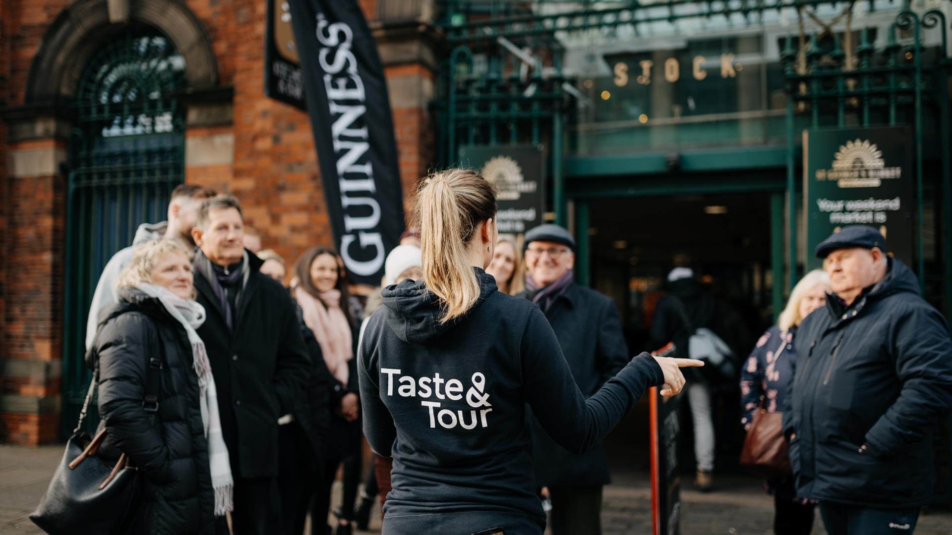 Group of guests listening to Taste & Tour tour guide outside of St George's Market on Belfast Food Tour