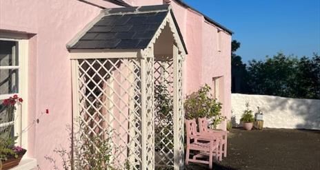 Outside view of the pink cottage with trellis porch