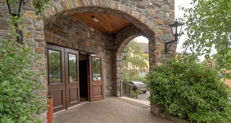 Hotel entrance under stone arches with an exit to a car park.