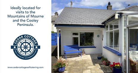 A view of the exterior of Cedar Cottage. A white cottage with blue accents.