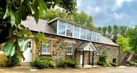 A renovated stone cottage with second floor windows.