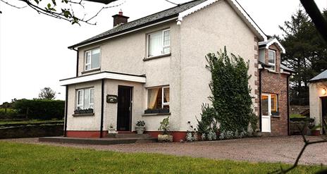 Image of a white two story house with climbing vines up the side