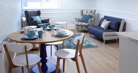 Open plan dining and living area with sofa, 2 armchairs and table and 3 chairs