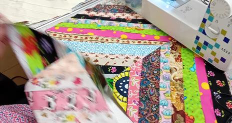 Sewing machine and patchwork quilt in progress at Midtown Makers workshop