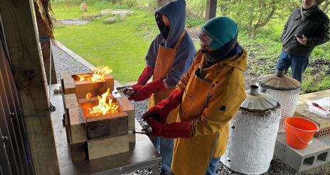 Pots covered with wood shaving being set alight using a blow torch