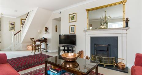 Living room with a coffee table, fireplace, TV, desk and a staircase.