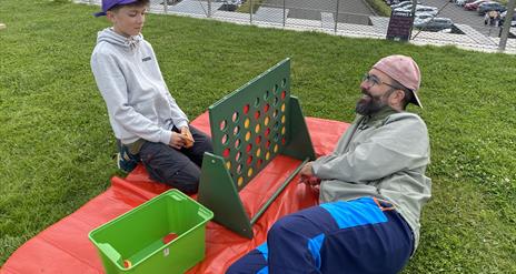 Two visitors enjoying a game of GIANT Connect 4 on the roof of the Giant's Causeway Visitor Centre