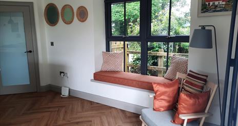A room with a seat with cushions and a window seat.