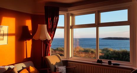 Looking through the front room bay window at a sea view, early in the morning.