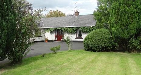 Outside of cottage, garden and trees in image