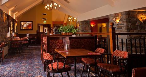 A restaurant dining area with tables, chairs and a seating booth.