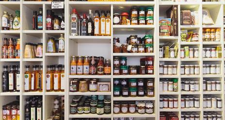 A wall covered with shelves of sauces, spreads and other food products.