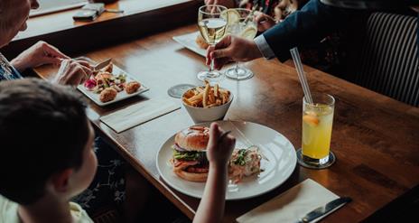 A family enjoying dinner and being served wine.