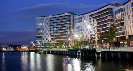 A curving apartment building at night on a seaside walkway.