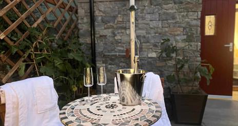 outdoor seating area with two glasses and a bottle of champagne