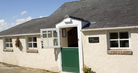 Image shows front of cottage with green stable door as entrance