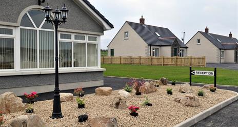 Image shows front of cottages with sign pointing to Reception