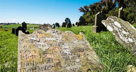 Close up photo of one of the gravestones, with others within view