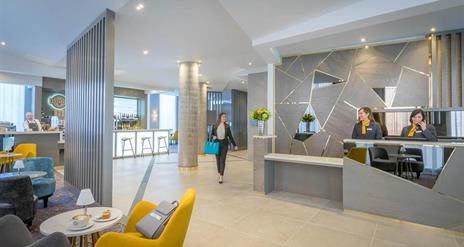 A woman walking through reception while receptionists work.