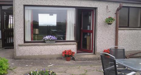 Photo of entrance to accommodation and seating area in yard