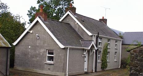 A side angle view of the front of a large grey house.