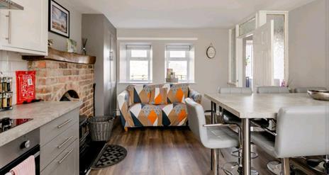 Open plan sitting area with kitchen table front door and a fireplace.